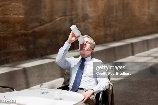 businessman looking up through rolled up paperwork - killing time stock pictures, royalty-free photos & images