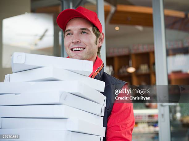 delivery man carrying stack of pizza boxes - pizza delivery stock pictures, royalty-free photos & images