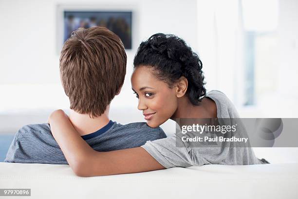 woman with arm around man on sofa watching tv - back of sofa stock pictures, royalty-free photos & images