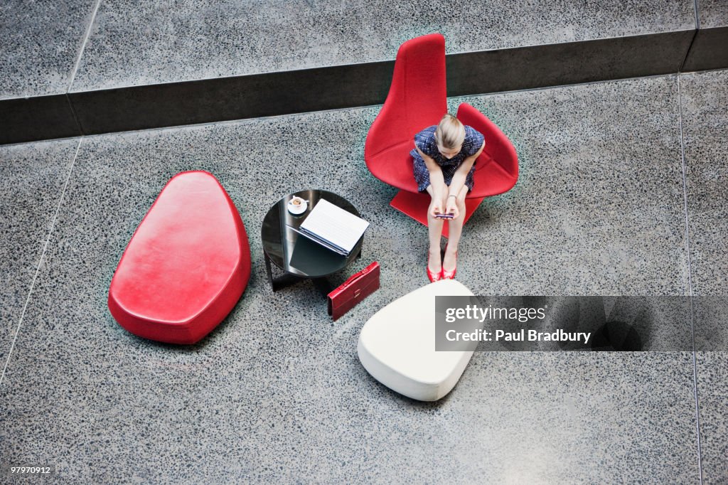 Mulher de Negócios segurando um telefone celular moderno do lobby