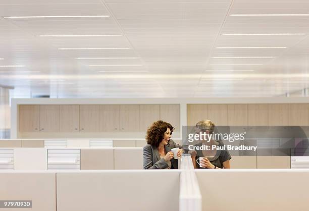 businesswomen with coffee gossiping in office cubicles - koffiepauze stockfoto's en -beelden