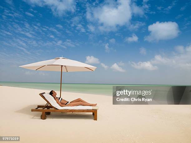 woman laying on lounge chair under beach umbrella - turks and caicos islands stock pictures, royalty-free photos & images