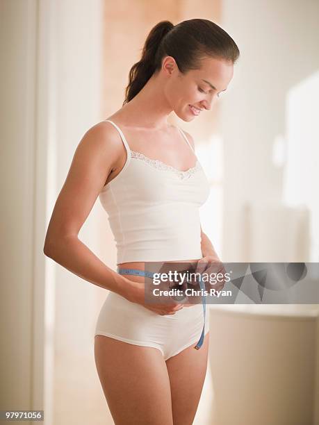woman measuring waist with tape measure - smiling woman waist up stock pictures, royalty-free photos & images