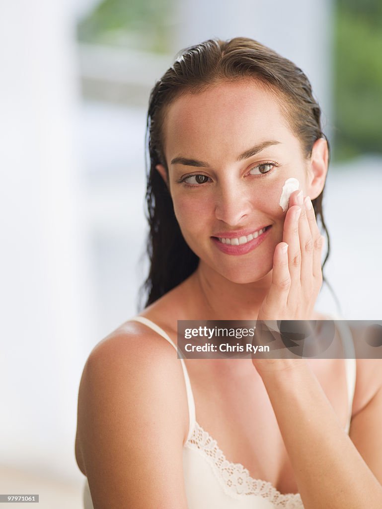 Woman applying moisturizer to face