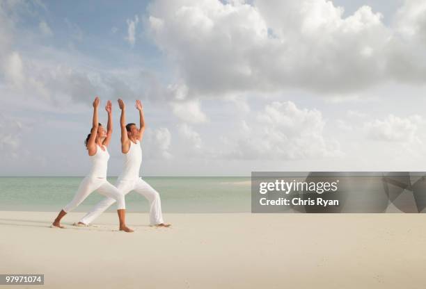 man in warrior 1 yoga pose on beach - warrior 1 stock pictures, royalty-free photos & images