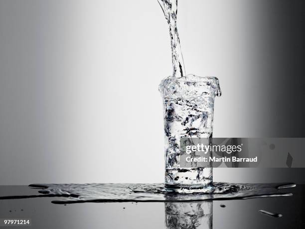 agua vertiendo en vidrio y abundantes - derramar fotografías e imágenes de stock