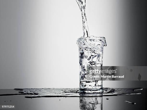 water pouring into glass and overflowing - drinking glass stock pictures, royalty-free photos & images