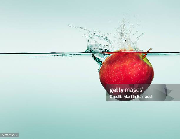 apple splashing in water - drijven stockfoto's en -beelden