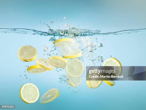 scheiben zitronen planschen im wasser - citrus fruit stock-fotos und bilder