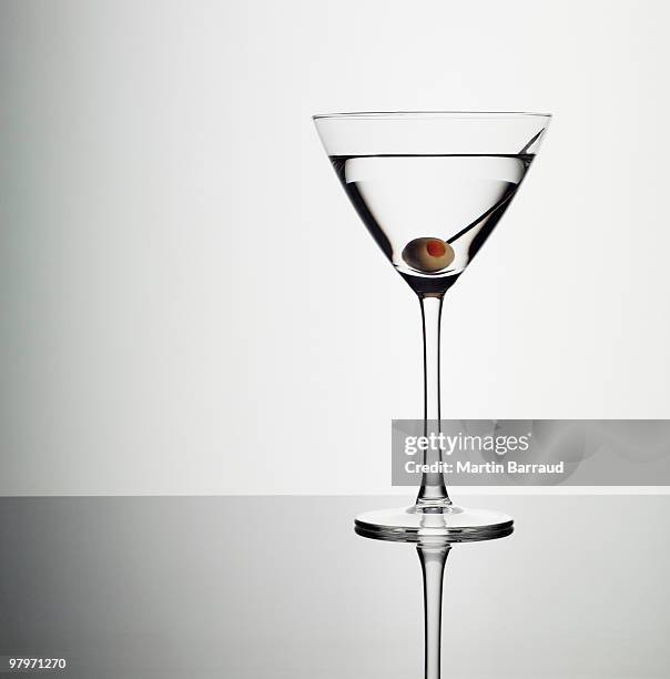 martini in glass with green olive - martini stockfoto's en -beelden
