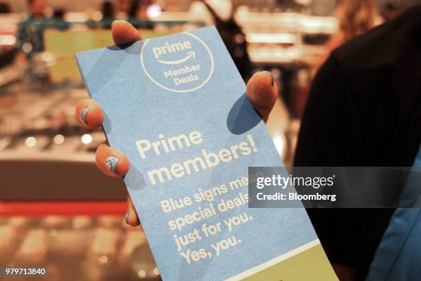 Representative holds pamphlets about special deals offered to Amazon.com Inc. Prime members during the grand opening of a Whole Foods Market Inc....