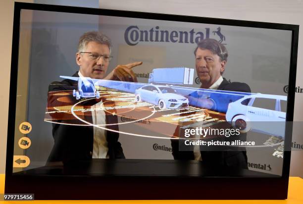 March 2018, Germany, Hannover: Chief executive Elmar Degenhart and chief financial officer Wolfgang Schaefer standing behind a television showing the...