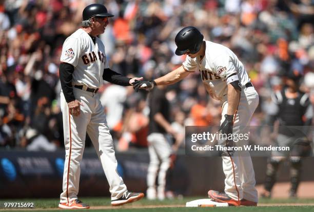 Nick Hundley of the San Francisco Giants is congratulated by third base coach Ron Wotus after Hundley slid into third base safe against the Miami...