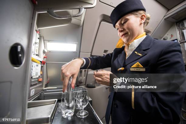 March 2018, Germany, Frankfurt: Lufthansa flight attendant Mrs Meyer prepares glasses with drinks for boarding passengers on an Airbus A 321...