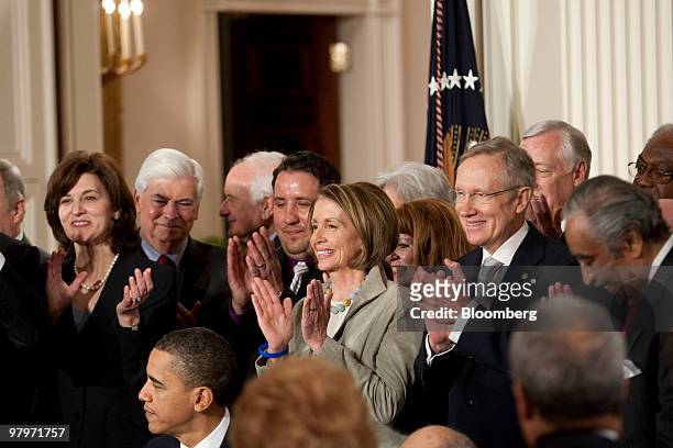 House Speaker Nancy Pelosi, center, and Senate Majority Harry Reid, right, clap after U.S. President Barack Obama signed the health insurance reform...