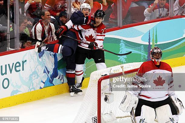 Scott Niedermayer of Canada checks Dustin Brown of USA behind the net as goaltender Roberto Luongo of Canada looks on during the ice hockey men's...
