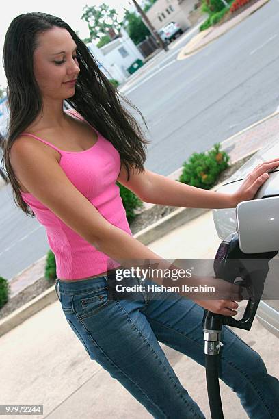 beautiful young woman filling car at gas station - woman smiling facing down stock pictures, royalty-free photos & images