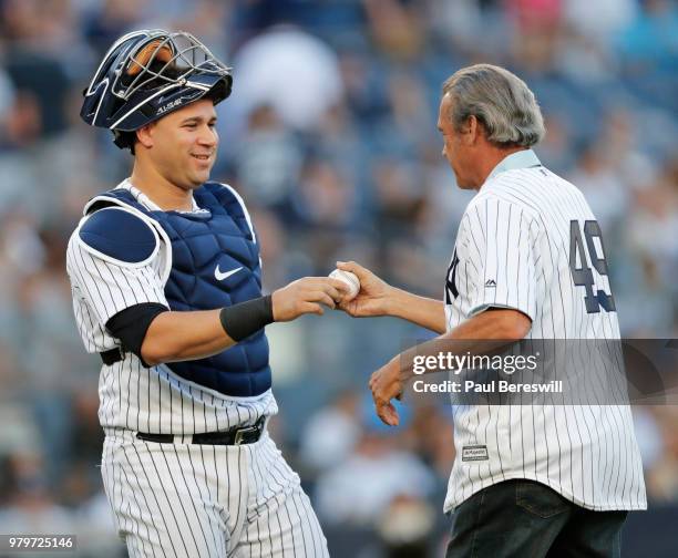 Gary Sanchez of the New York Yankees hands the ball to former Yankees pitcher Ron Guidry after Guidry threw out the first pitch before an MLB...