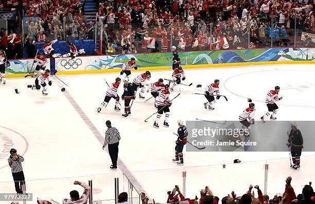 Members of Team Canada skate from the bench area toward teammate Sidney Crosby in the corner to celebrate their 3-2 overtime victory after the ice...