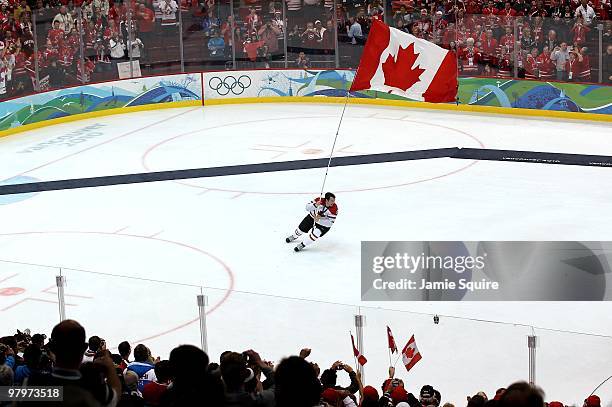 Drew Doughty of Canada skates around the rink with the Canadian national flag following Canada's 3-2 overtime victory during the ice hockey men's...