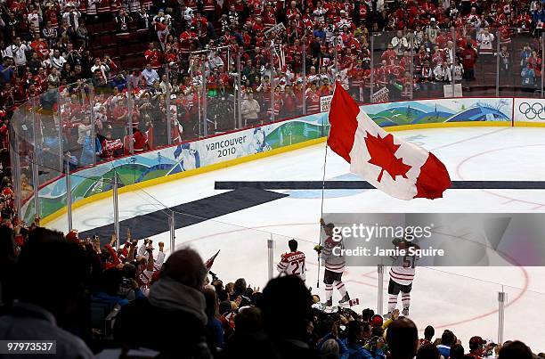 Corey Perry of Canada waves the Canadian national flag following his team's 3-2 overtime victory during the ice hockey men's gold medal game between...