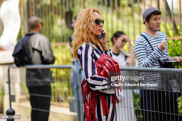 Elina Halimi wears a black and white striped outfit, a red bag, white sneakers, outside Y/Project, during Paris Fashion Week - Menswear Spring-Summer...