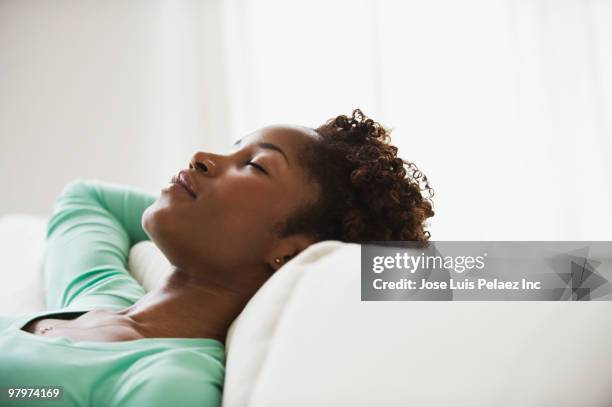 african woman napping on sofa - taking a nap stock-fotos und bilder