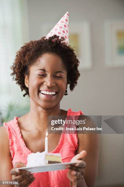 african woman holding birthday slice of cake - woman holding cake stock-fotos und bilder