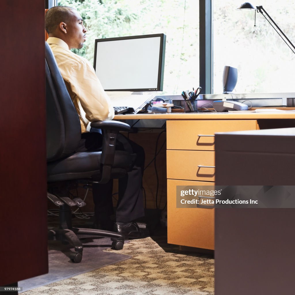 Mixed race businessman daydreaming at desk