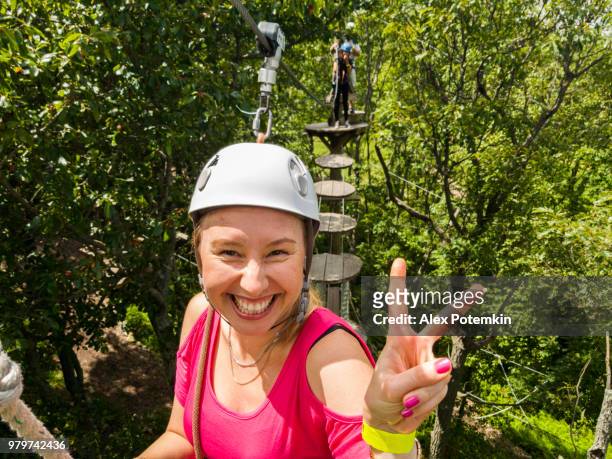 the adult woman passing the zip line. mobile photo. - alex potemkin or krakozawr stock pictures, royalty-free photos & images