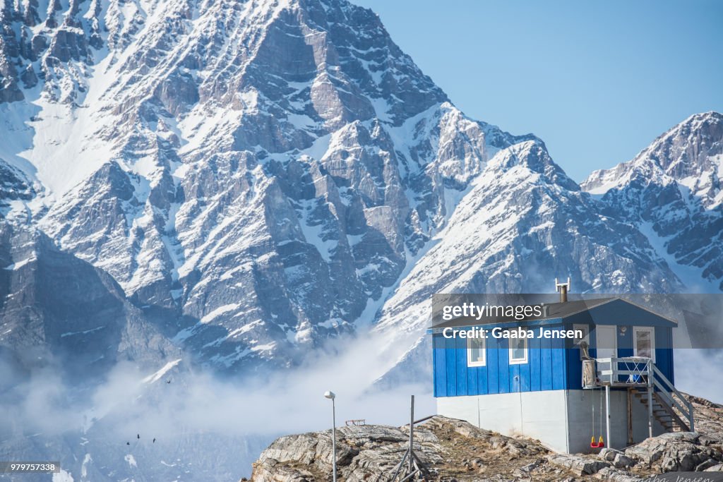 Blue wooden house with snowcapped mountains in background, Ukkusissat, Qaasuitsup, Uummannaq fjord, Greenland
