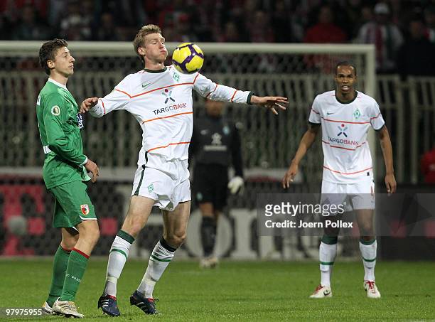 Per Mertesacker of Bremen and Jens Hegeler of Augsburg compete for the ball during the DFB Cup Semi Final match between SV Werder Bremen and FC...