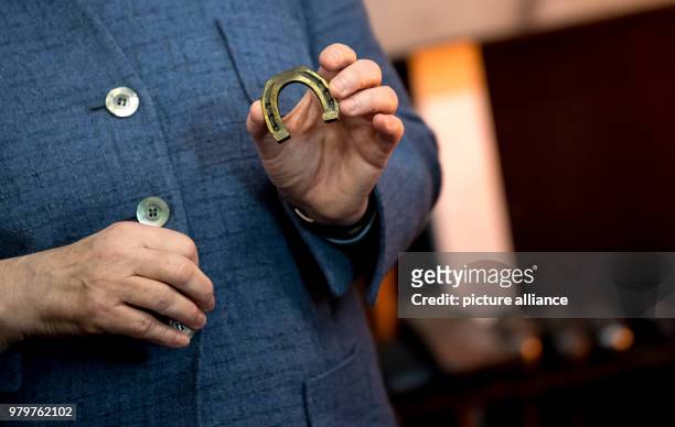 March 2018, Germany, Munich: German Chancellor Angela Merkel of the Christian Democratic Union holds up a horseshoe manufactured by 'Krellsche...