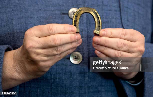 March 2018, Germany, Munich: German Chancellor Angela Merkel of the Christian Democratic Union holds up a horseshoe manufactured by 'Krellsche...