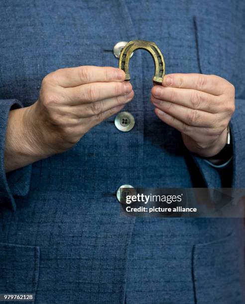 March 2018, Germany, Munich: German Chancellor Angela Merkel of the Christian Democratic Union holds up a horseshoe manufactured by 'Krellsche...