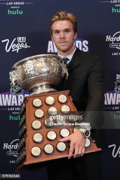 Connor McDavid of the Edmonton Oilers poses with the Art Ross Trophy as the NHL's leading scorer in the press room at the 2018 NHL Awards presented...