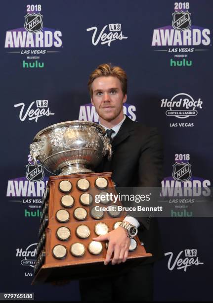 Connor McDavid of the Edmonton Oilers poses with the Art Ross Trophy as the NHL's leading scorer in the press room at the 2018 NHL Awards presented...