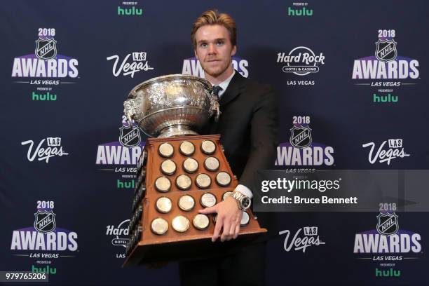 Connor McDavid of the Edmonton Oilers poses with the Art Ross Trophy as the NHL's leading scorer in the press room at the 2018 NHL Awards presented...