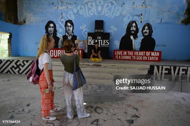 This picture taken on June 18 a tourist takes pictures of a mural at the now-derelict ashram visited by the Beatles 50 years ago in Rishikesh in...