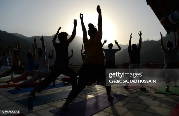 This picture taken on June 19 shows people practising yoga on a terrace at the Anand Prakash yoga ashram in Rishikesh in India's Uttarakhand state. -...