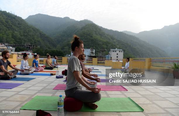This picture taken on June 19 shows people practising yoga on a terrace at the Anand Prakash yoga ashram in Rishikesh in India's Uttarakhand state. -...