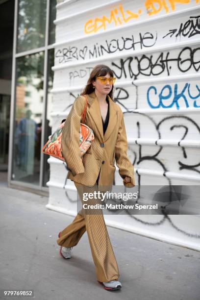 Guest is seen on the street during Paris Men's Fashion Week S/S 2019 wearing a gold suit with floral bag on June 20, 2018 in Paris, France.