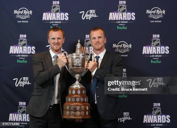 Henrik Sedin and Daniel Sedin of the Vancouver Canuks pose with the King Clancy Memorial Trophy in the press room at the 2018 NHL Awards presented by...