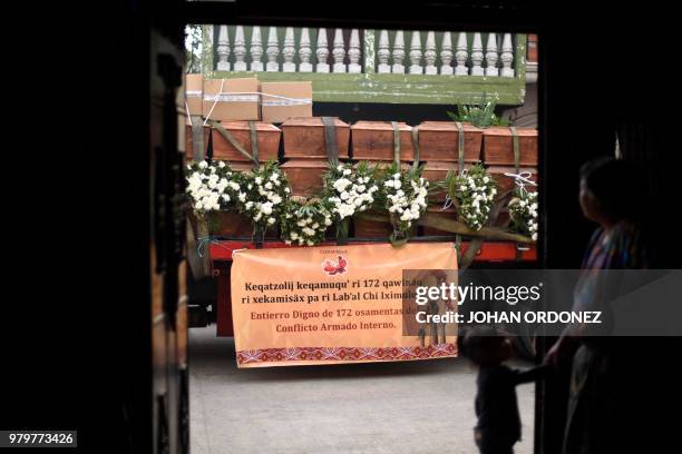 Local residents look on, as a truck transporting 172 urns containing the remains of victims of the Guatemalan armed conflict , arrives in San Juan...