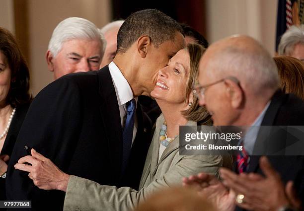 President Barack Obama, left, congratulates House Speaker Nancy Pelosi after signing the health insurance reform bill in the East Room of the White...