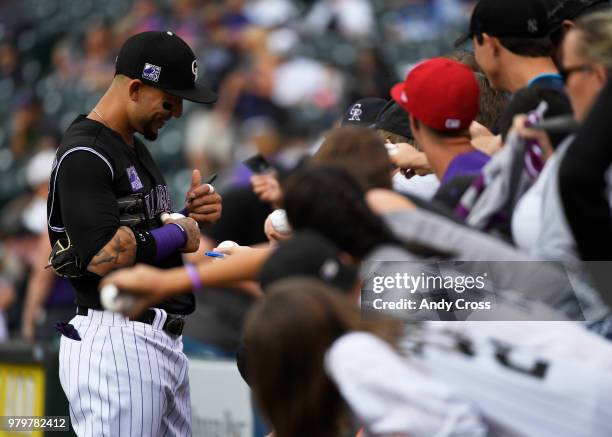 Colorado Rockies right fielder Carlos Gonzalez signs autographs coming off the field after warming up before the game against the New York Mets at...