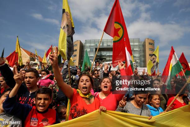 Kurds wave the flag of the Kurdish People's Protection Units militia and hold posters of Kurdish nationalist leader Abdullah Ocalan while shouting...