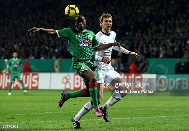 Per Mertesacker of Bremen and Nando Rafael of Augsburg compete for the ball during the DFB Cup Semi Final match between SV Werder Bremen and FC...