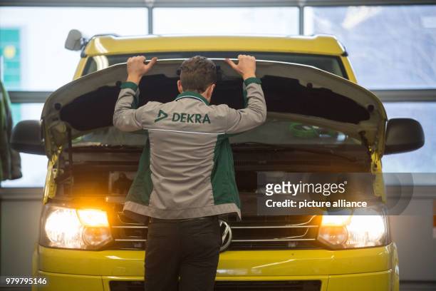 March 2018, Germany, Stuttgart: An employee of the vehicle inspection company Dekra opens the bonnet of a VW T5 diesel in the course of a general...