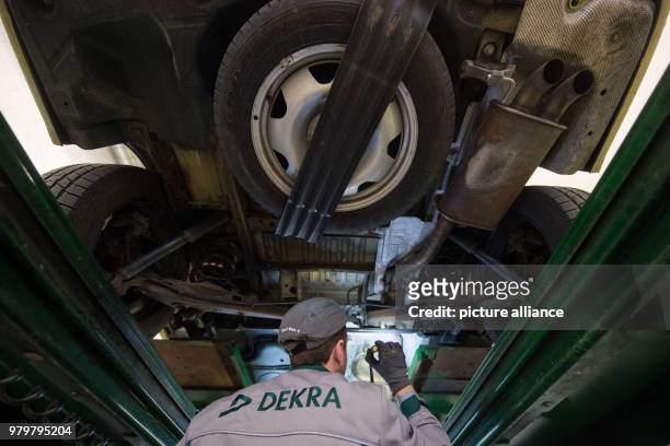 March 2018, Germany, Stuttgart: An employee of the vehicle inspection company Dekra checks the underbody of a VW T5 diesel in the course of a general...